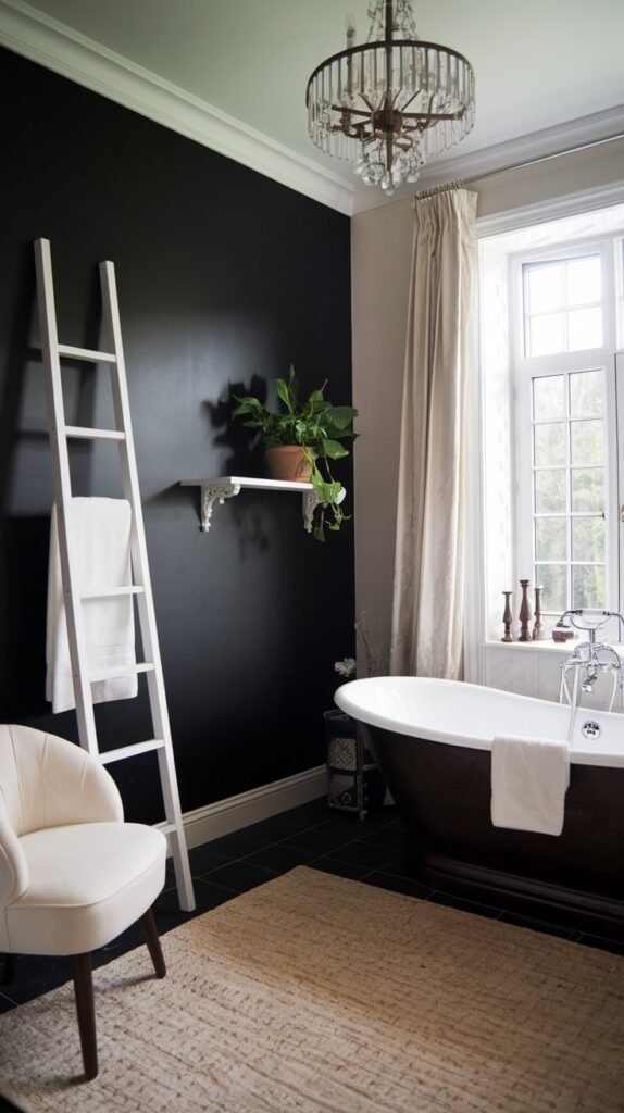 A luxurious bathroom with a black accent wall. There is a freestanding bathtub near the window. A white ladder leans against the black wall. There is a white shelf with a potted plant on the black wall. A white chair is placed near the shelf. The floor is covered with a beige rug. The room has a chandelier.