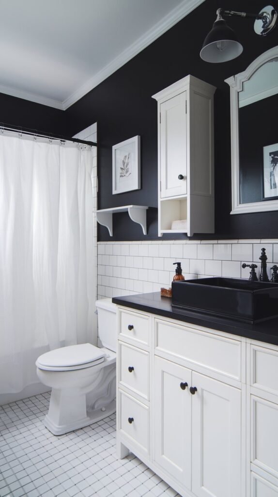 A bathroom with a black accent wall. There is a white vanity with a black countertop and a black sink. Above the sink is a white cabinet. There is a black lampshade on a white lamp. The floor is tiled with white and grey tiles. There is a white toilet and a white shower curtain. The wall has a white shelf and a white frame.