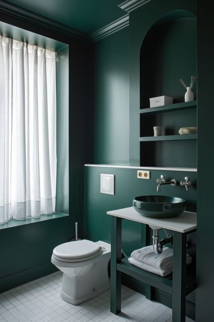 A bathroom with dark green walls, an arched alcove, and a white sink.