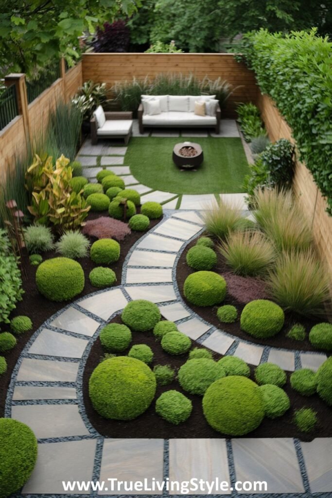 An aerial view of a narrow backyard with a winding stone pathway through lush greenery, leading to an outdoor seating area.