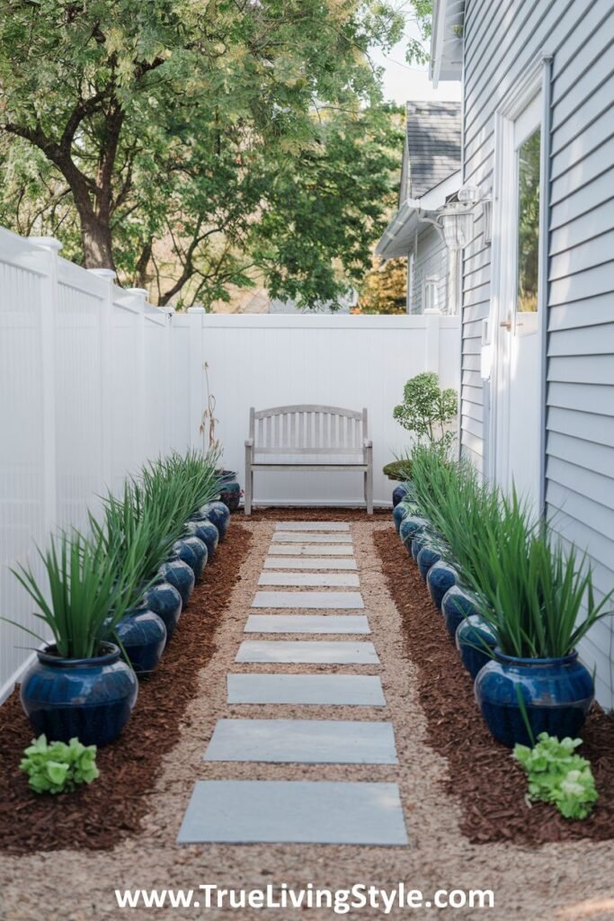 A narrow yard featuring a stone pathway lined with potted plants, leading to a bench.