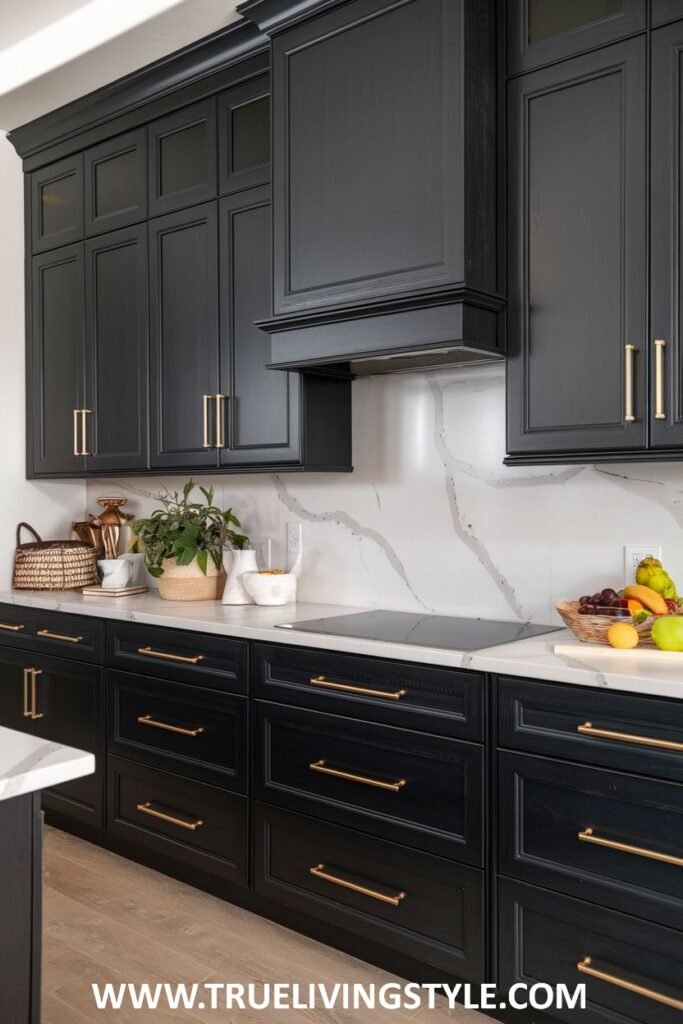 A kitchen featuring black cabinets with gold hardware and a white marble backsplash.