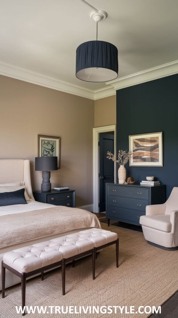 A sophisticated bedroom with a deep teal accent wall and beige walls. A bed with neutral bedding and a light-colored tufted bench is shown, along with a dark blue dresser and a light pink armchair.
