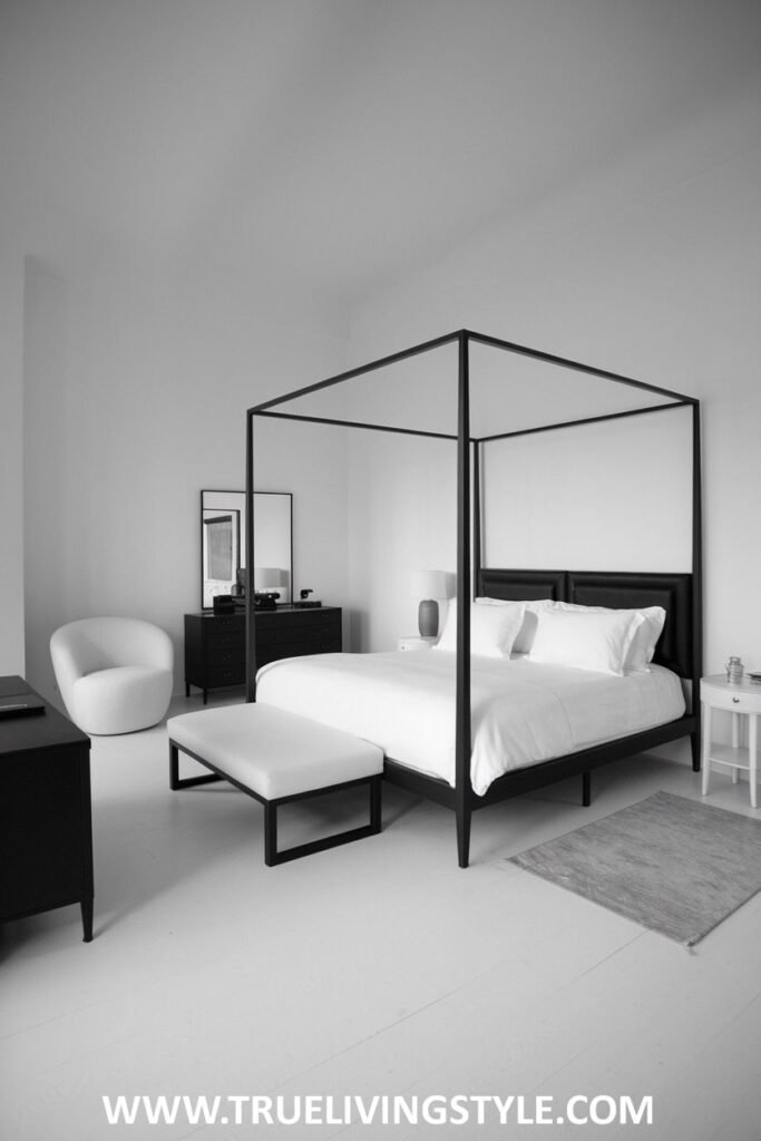 A minimalist bedroom features a black four-poster bed with white bedding and minimal accessories.