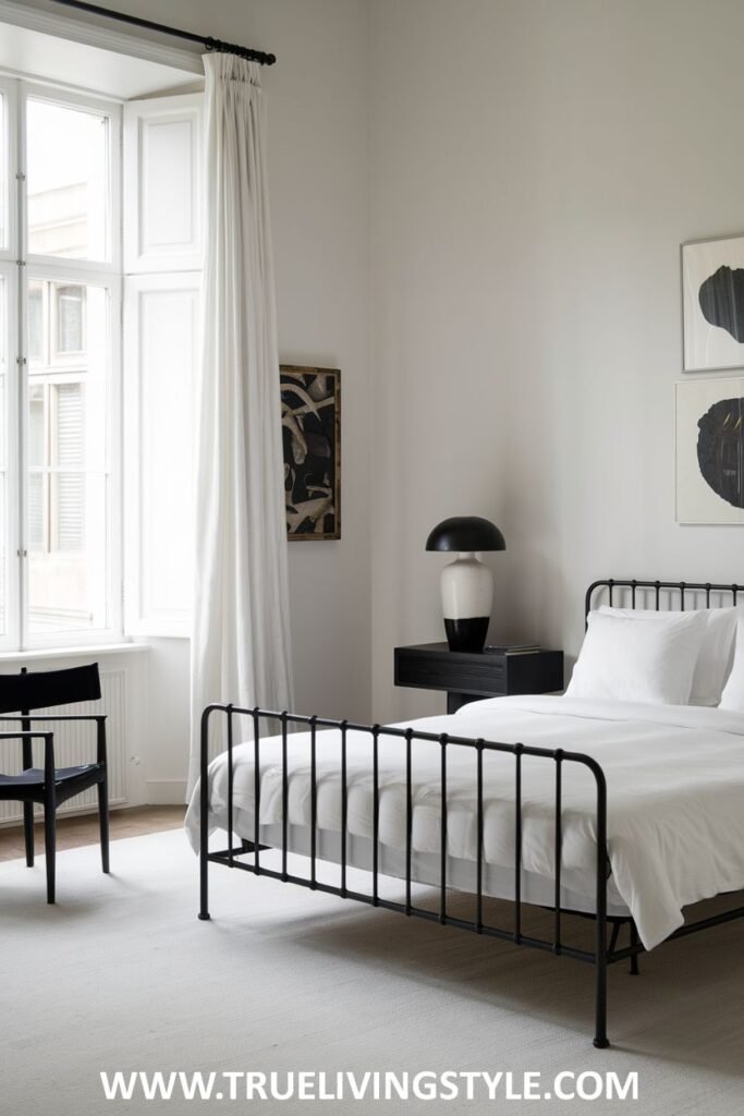 A black metal bed frame is paired with white walls and minimal accessories.