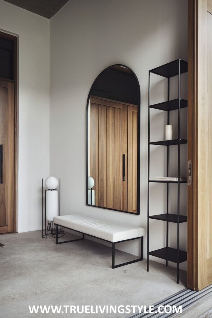 A hallway featuring a mirror, a white bench, and a black shelving unit.