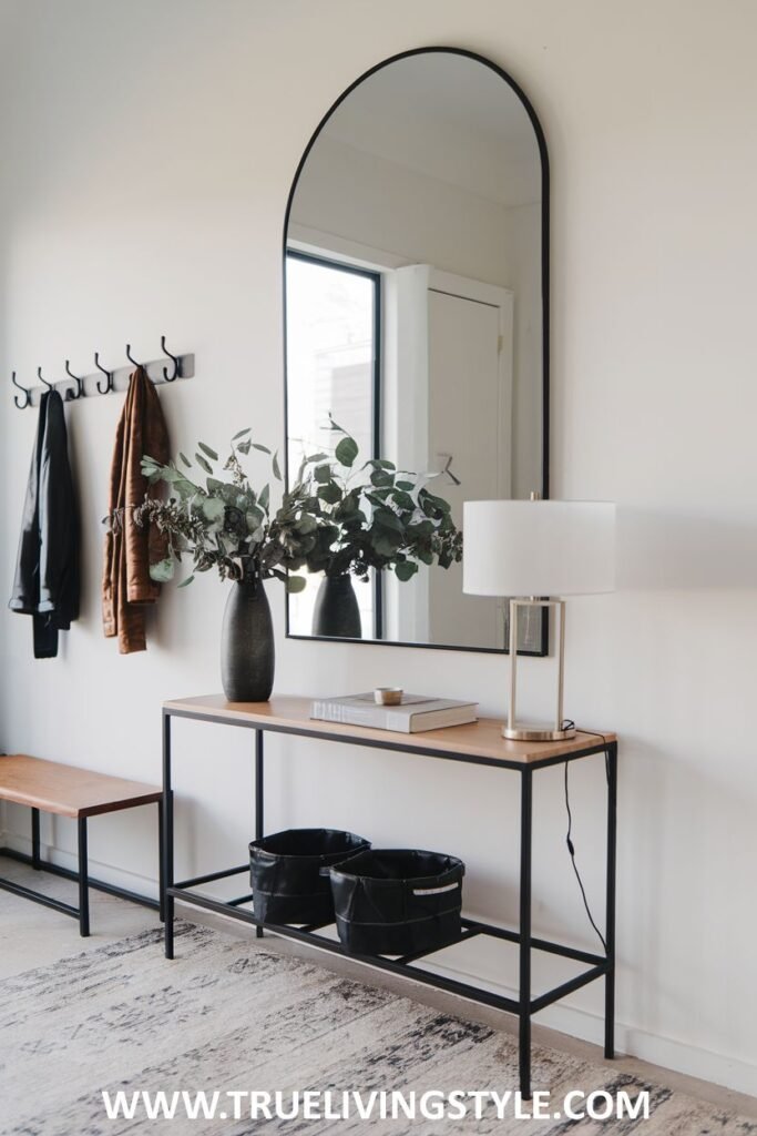 A console table with a mirror, lamp, vase, and baskets, accompanied by a bench and coat hooks.