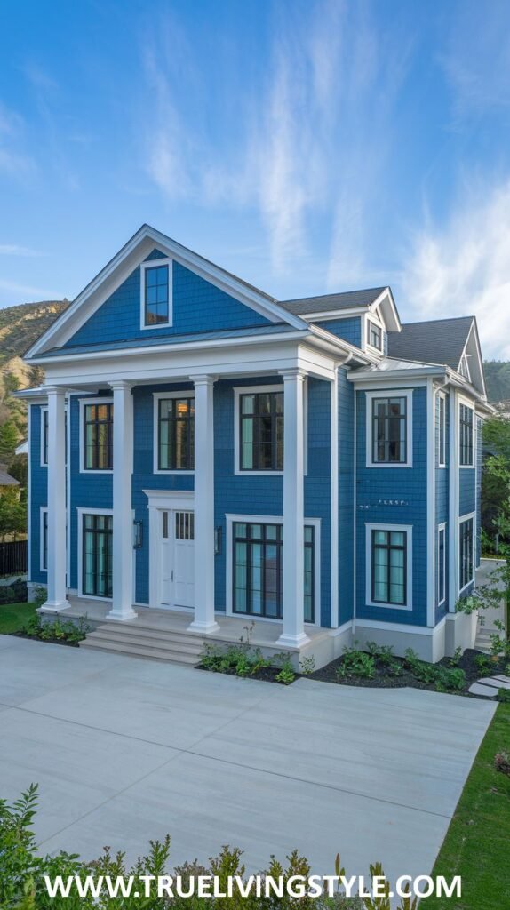 A stately colonial-style home painted in a classic blue, with a prominent white columned portico, white trim, and shingle siding.