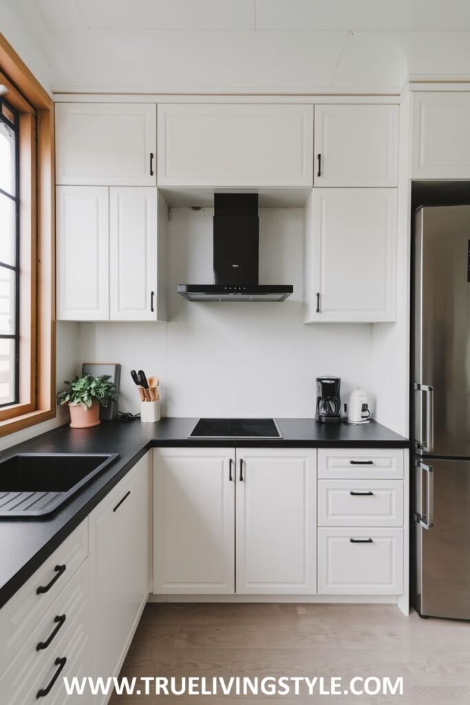 A kitchen with white cabinets, black countertops, and a stainless steel refrigerator.