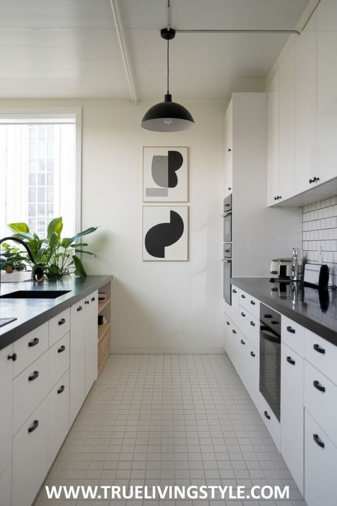 A minimalist kitchen featuring white cabinets, black countertops, and geometric art.