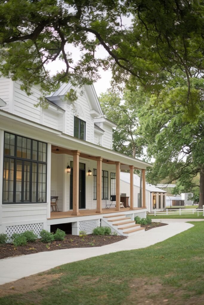 A long white farmhouse with a porch supported by wooden columns and railings. A winding pathway leads towards the house.
